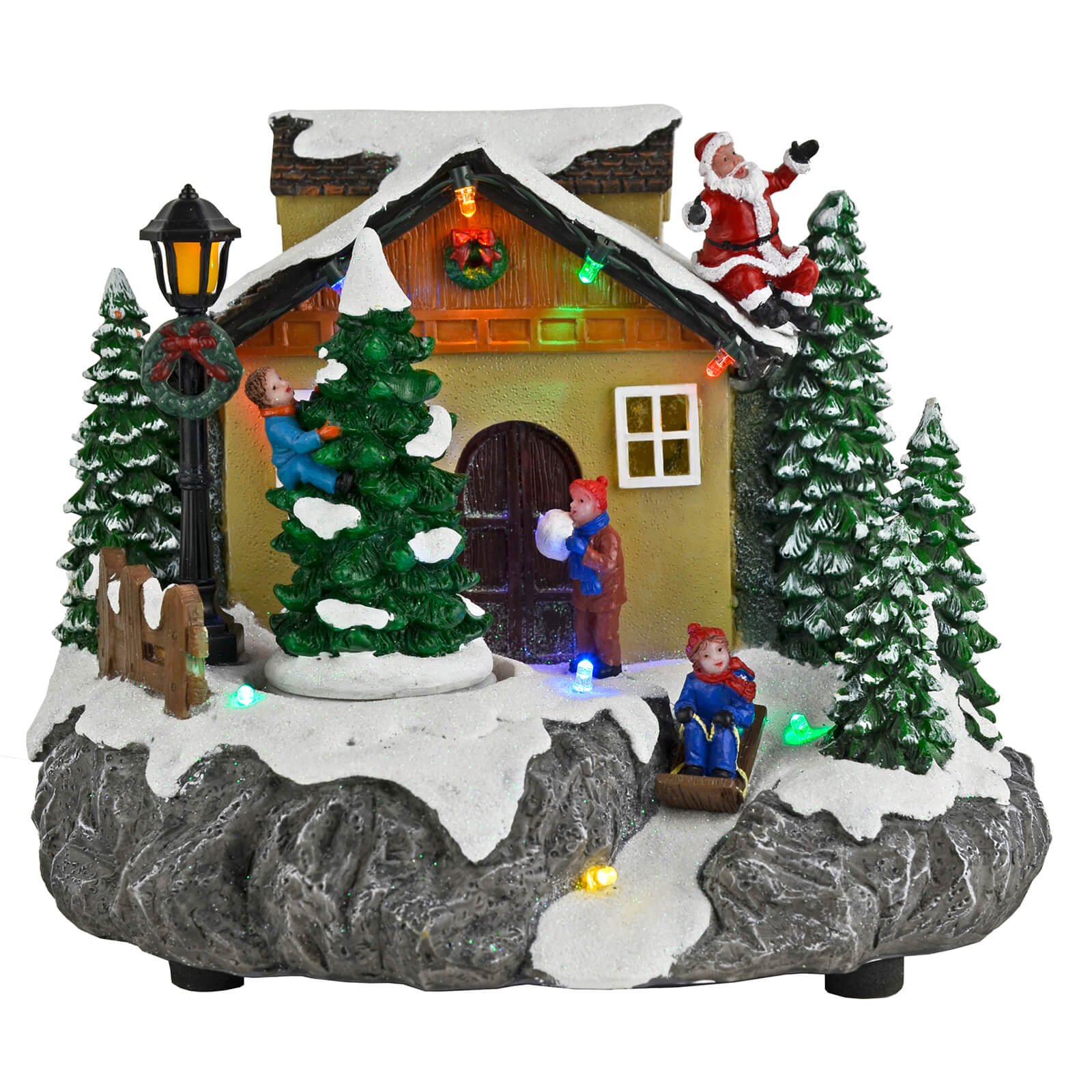 Light up village snow scene with Santa on the house roof, children climbing and sledging, lit by coloured LED lights